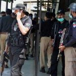 Police officers gather at an entry gate of district court following the killing of Tahir Ahmad Naseem, who was in court accused of insulting Islam, in Peshawar, Pakistan, Wednesday, July 29, 2020. (AP Photo/Muhammad Sajjad)