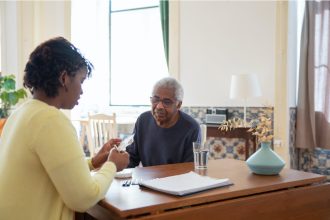 Nursing home staff providing medication assistance to senior man