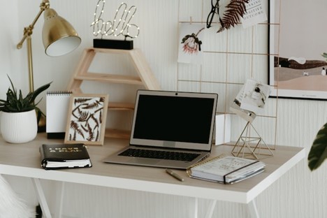 An organized work desk with a laptop, notebooks and positive messages