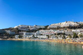 a crowded beach and buildings on a mountain in Gran Canaria